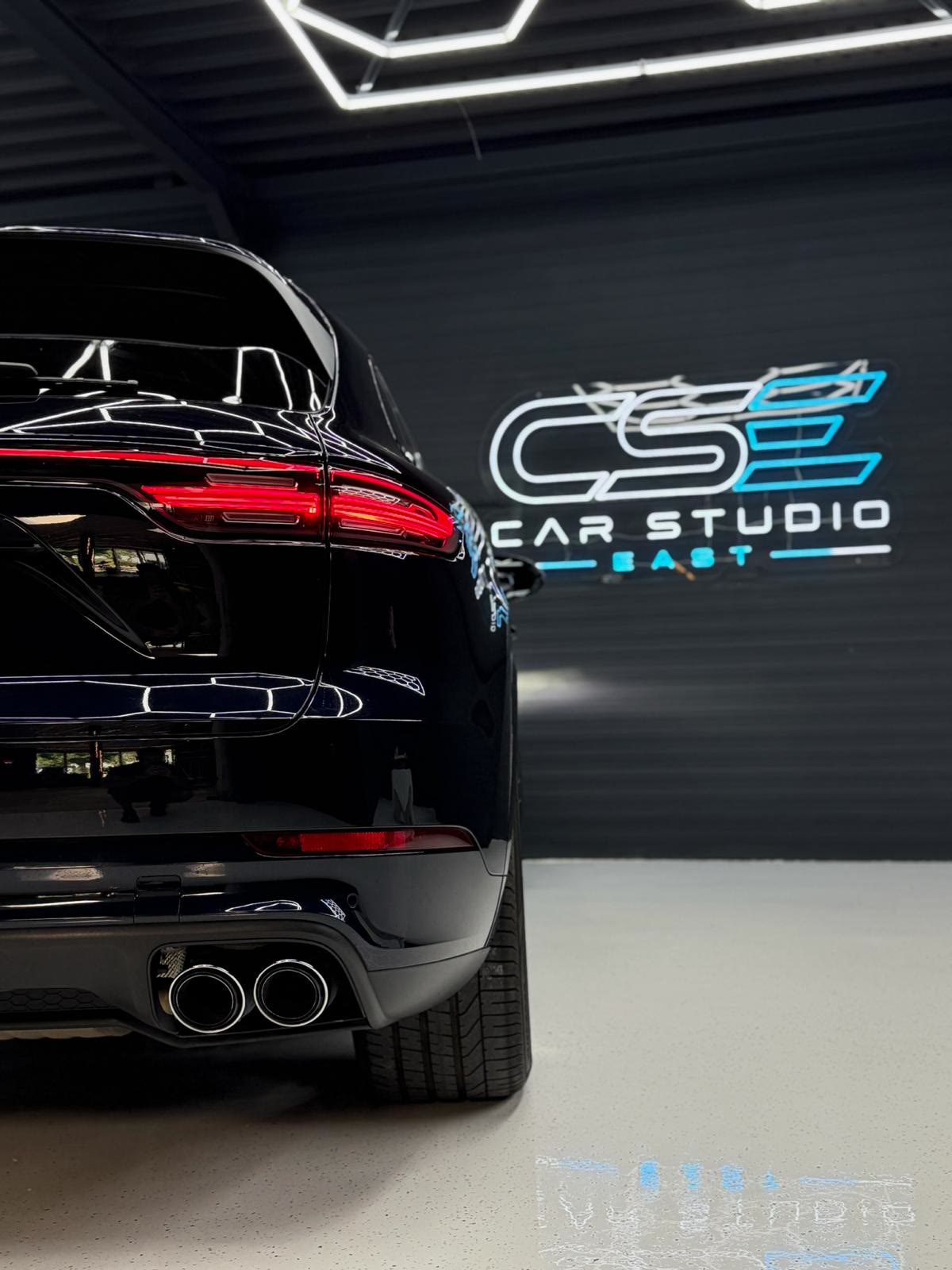 Zwarte Porsche voor het verlichte Car Studio East-logo