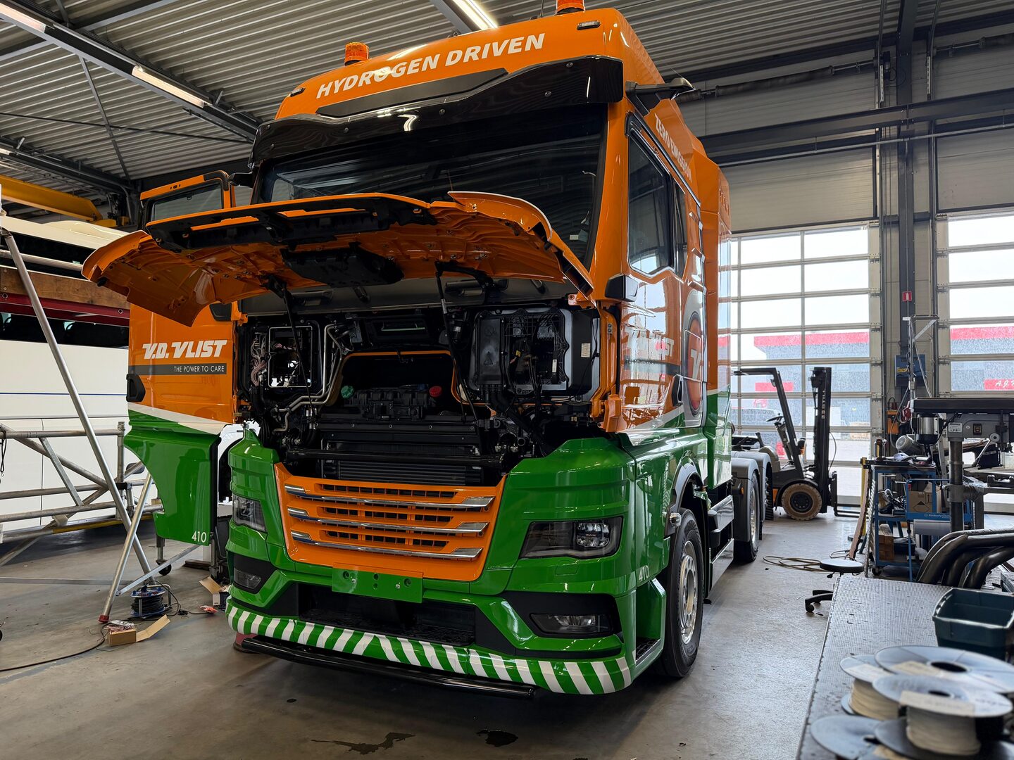 Oranje-groene vrachtwagen tijdens montage in de werkplaats
